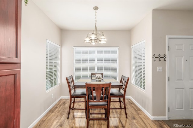 dining space with light wood finished floors, a chandelier, and baseboards