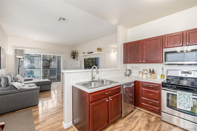 kitchen featuring stainless steel appliances, a sink, dark brown cabinets, and open floor plan