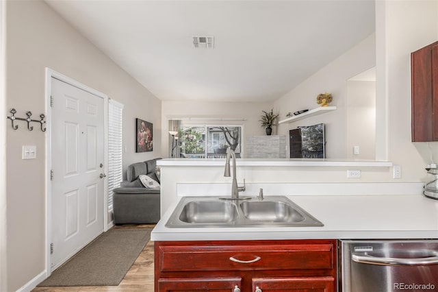 kitchen featuring a sink, stainless steel dishwasher, reddish brown cabinets, and light countertops