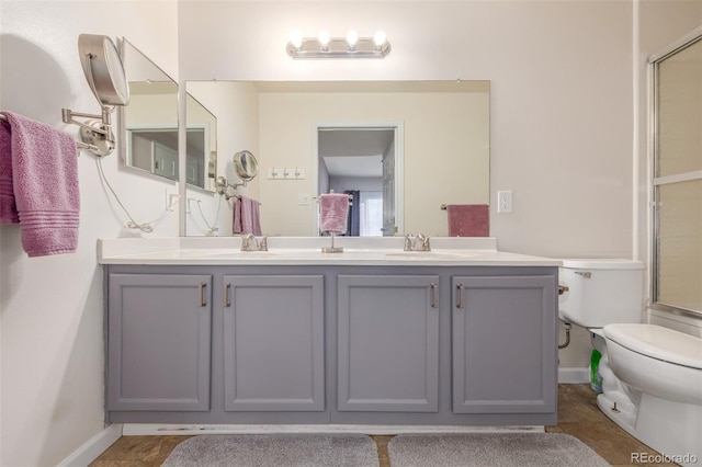 bathroom featuring toilet, double vanity, baseboards, and a shower with door