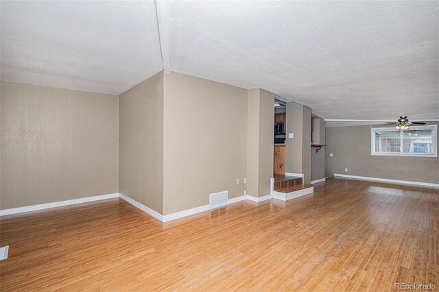 28532 Shadow Mountain Dr, Conifer, CO 80433 - unfurnished living room featuring light wood-style flooring, a ceiling fan, a textured ceiling, and baseboards