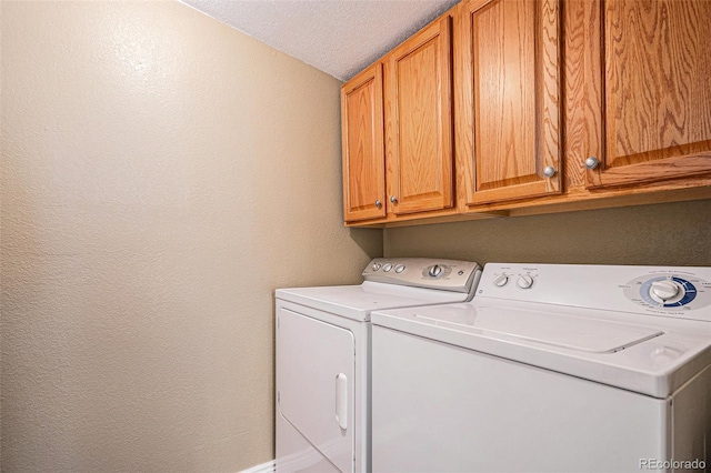 laundry room featuring independent washer and dryer, a textured ceiling, and cabinets