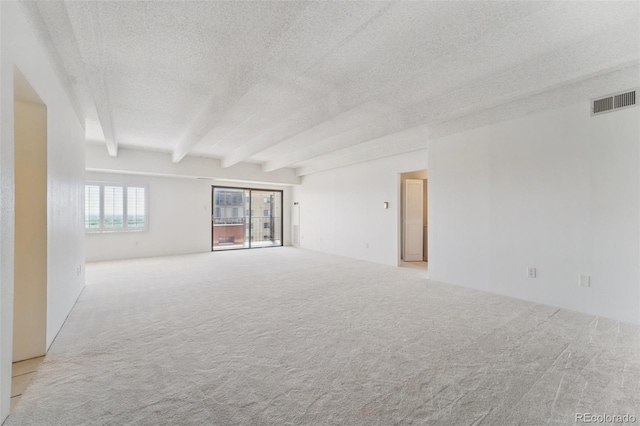 unfurnished room featuring a textured ceiling, beamed ceiling, visible vents, and carpet