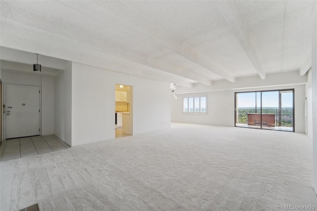 spare room featuring carpet floors, a textured ceiling, and beamed ceiling