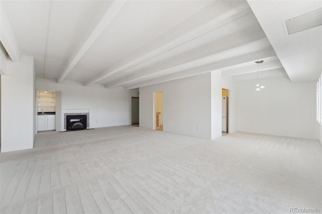 unfurnished living room with carpet floors, beamed ceiling, visible vents, and a fireplace with flush hearth