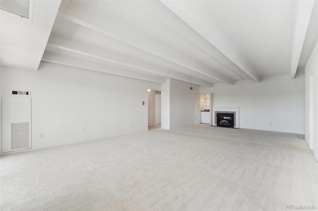 unfurnished living room with visible vents, a fireplace, beam ceiling, and light carpet