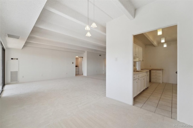 unfurnished living room featuring light colored carpet, beam ceiling, and visible vents