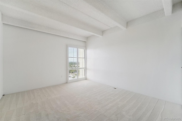 carpeted empty room with a textured ceiling and beamed ceiling