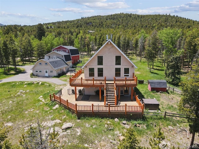 31551 Black Widow Dr, Conifer, CO 80433 - rear view of property featuring a view of trees, a wooden deck, a storage unit, and stucco siding