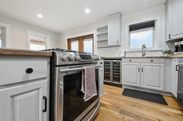 31551 Black Widow Dr, Conifer, CO 80433 - kitchen with wine cooler, stainless steel stove, white cabinets, open shelves, and light wood-type flooring