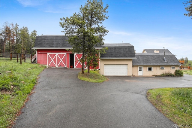 31551 Black Widow Dr, Conifer, CO 80433 - dutch colonial featuring a shingled roof, a barn, driveway, a garage, and an outbuilding