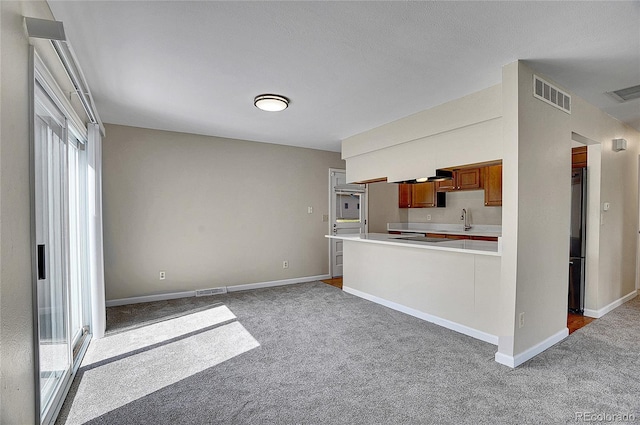 9099 W Harvard Pl, Lakewood, CO 80227 - kitchen featuring carpet floors, a sink, light countertops, brown cabinetry, and baseboards