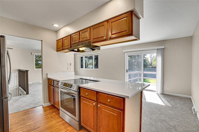 9099 W Harvard Pl, Lakewood, CO 80227 - kitchen with appliances with stainless steel finishes, under cabinet range hood, light countertops, brown cabinetry, and recessed lighting