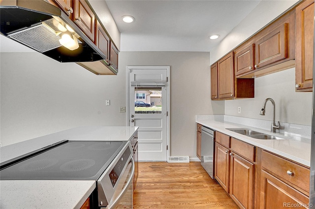 9099 W Harvard Pl, Lakewood, CO 80227 - kitchen with appliances with stainless steel finishes, under cabinet range hood, a sink, light wood-style floors, and light countertops