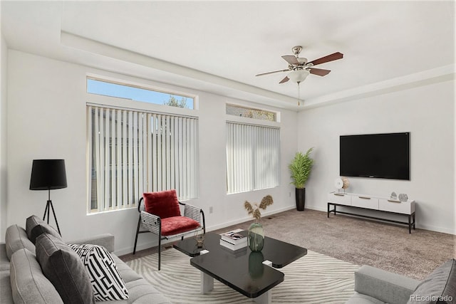 living room featuring carpet floors, a raised ceiling, and ceiling fan