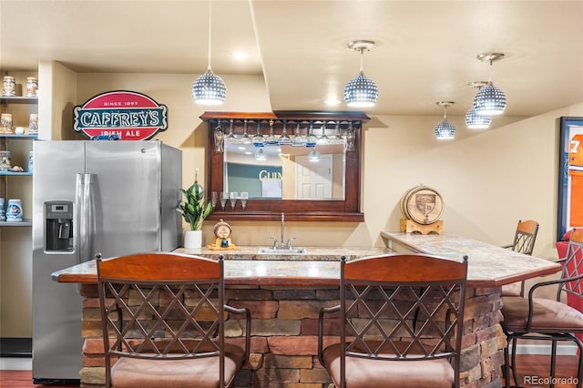 6858 Otis Ct, Arvada, CO 80003 - kitchen featuring stainless steel refrigerator with ice dispenser, a breakfast bar area, light stone countertops, and hanging light fixtures