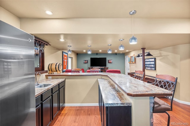 6858 Otis Ct, Arvada, CO 80003 - kitchen with freestanding refrigerator, light wood finished floors, a kitchen bar, hanging light fixtures, and light countertops