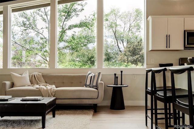 living room featuring light wood-type flooring, baseboards, and plenty of natural light