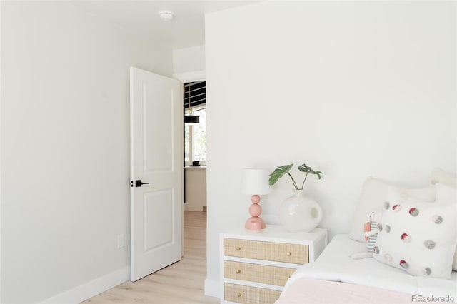 bedroom with light wood finished floors and baseboards