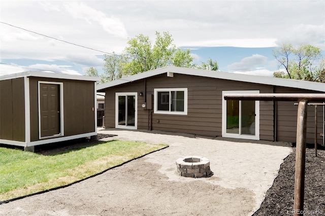 back of house featuring a fire pit, an outdoor structure, a patio, and a storage unit