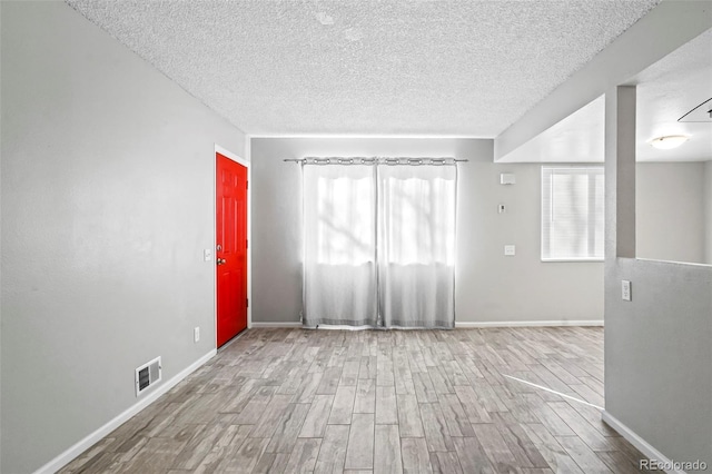 unfurnished room featuring a textured ceiling and light hardwood / wood-style floors