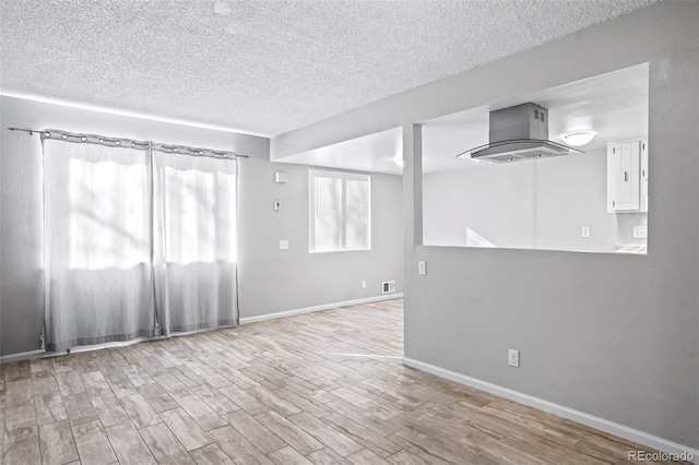 spare room featuring a textured ceiling and light hardwood / wood-style flooring