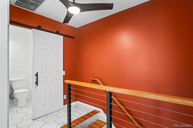 interior space featuring a barn door, tile patterned floors, and ceiling fan