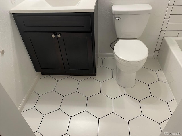 bathroom with tile patterned flooring, vanity, a bath, and toilet