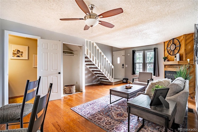 living room featuring ceiling fan, a textured ceiling, and hardwood / wood-style flooring