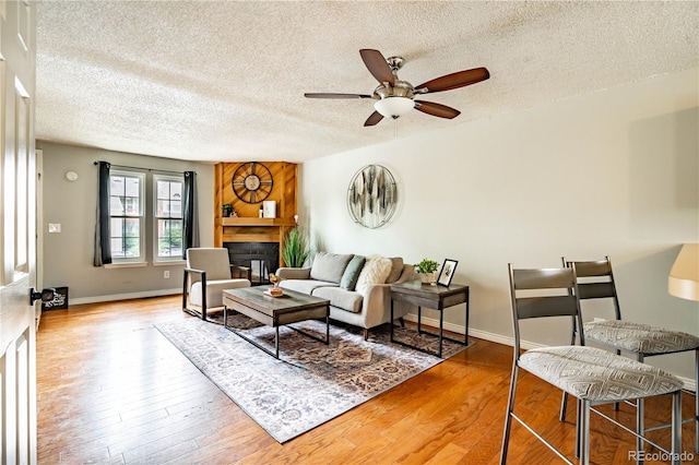 living room featuring ceiling fan, wood-type flooring, and a textured ceiling