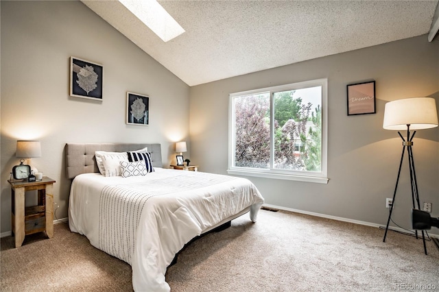 bedroom with vaulted ceiling with skylight, carpet floors, and a textured ceiling