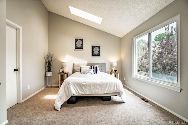 bedroom featuring carpet flooring, lofted ceiling with skylight, a textured ceiling, and multiple windows