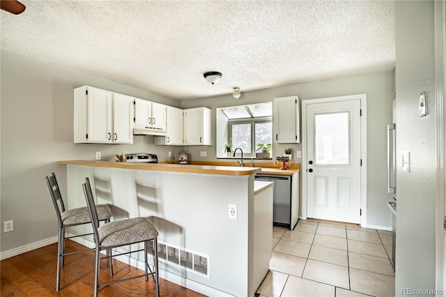 kitchen with kitchen peninsula, white cabinetry, stainless steel dishwasher, and custom exhaust hood