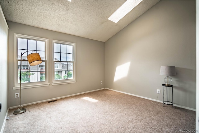 carpeted empty room with a textured ceiling and vaulted ceiling with skylight