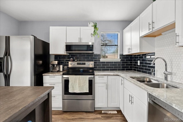 kitchen with white cabinetry, appliances with stainless steel finishes, decorative backsplash, and a sink