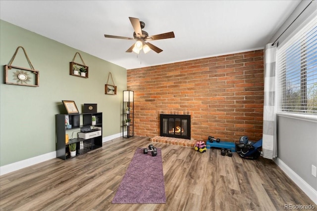 unfurnished living room featuring a fireplace, ceiling fan, baseboards, and wood finished floors