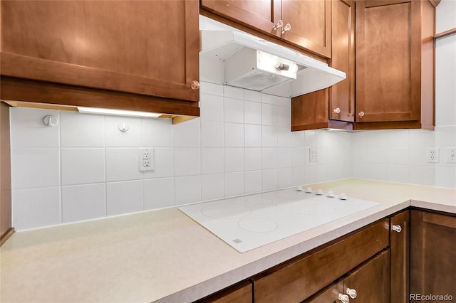 3022 Blackhawk St, Aurora, CO 80011 - kitchen featuring brown cabinetry, tasteful backsplash, white electric stovetop, light countertops, and under cabinet range hood