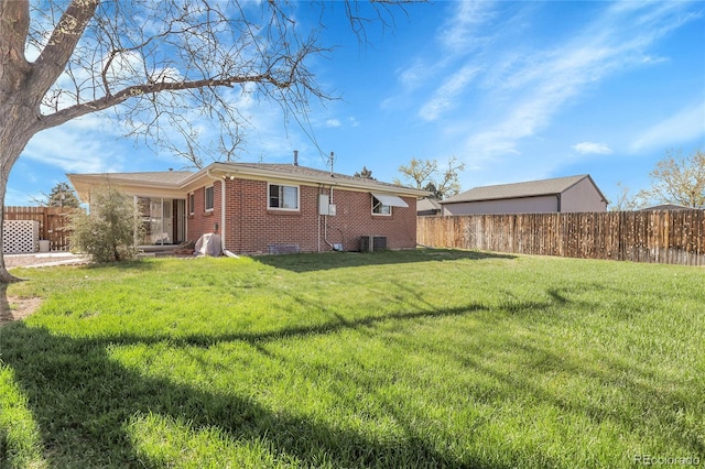 3022 Blackhawk St, Aurora, CO 80011 - back of property with a lawn, central AC unit, a fenced backyard, and brick siding