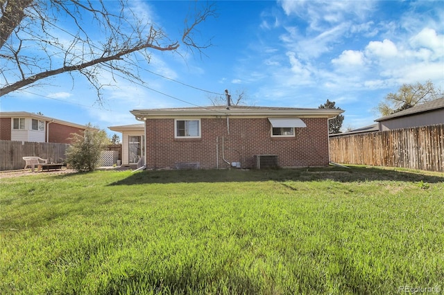 3022 Blackhawk St, Aurora, CO 80011 - rear view of house with brick siding, a fenced backyard, a lawn, and central air condition unit