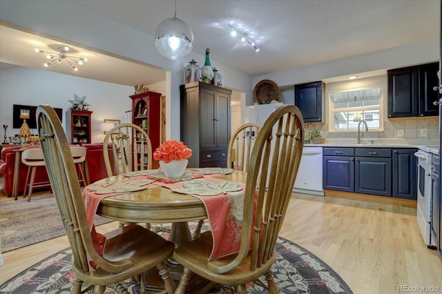 dining room with sink, a notable chandelier, and light wood-type flooring