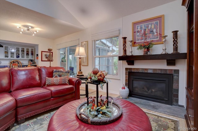 living room featuring a textured ceiling, vaulted ceiling, and a tiled fireplace