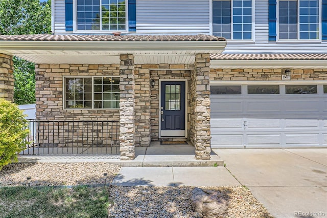 18807 E 51st Pl, Denver, CO 80249 - doorway to property with a porch, an attached garage, a tile roof, and stone siding