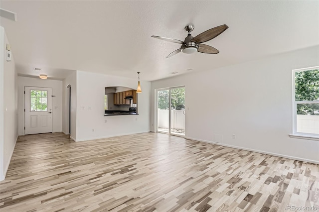 18807 E 51st Pl, Denver, CO 80249 - unfurnished living room featuring light wood-style floors, a ceiling fan, and healthy amount of natural light