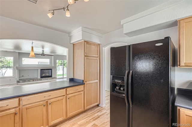 18807 E 51st Pl, Denver, CO 80249 - kitchen featuring black fridge with ice dispenser, light brown cabinetry, light wood-type flooring, a glass covered fireplace, and arched walkways
