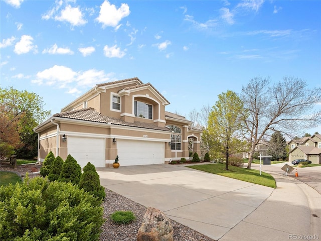 mediterranean / spanish house featuring a garage, stucco siding, concrete driveway, and a tile roof