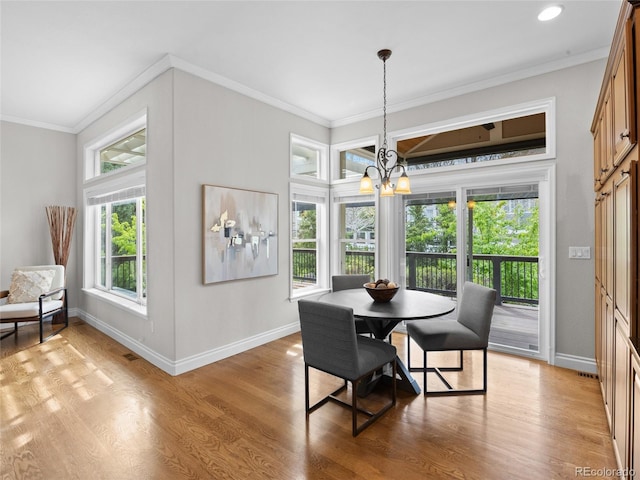 dining area featuring baseboards, a notable chandelier, ornamental molding, and light wood-style flooring