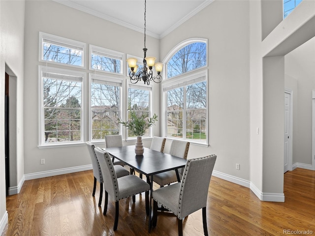 dining room featuring an inviting chandelier, baseboards, crown molding, and a towering ceiling