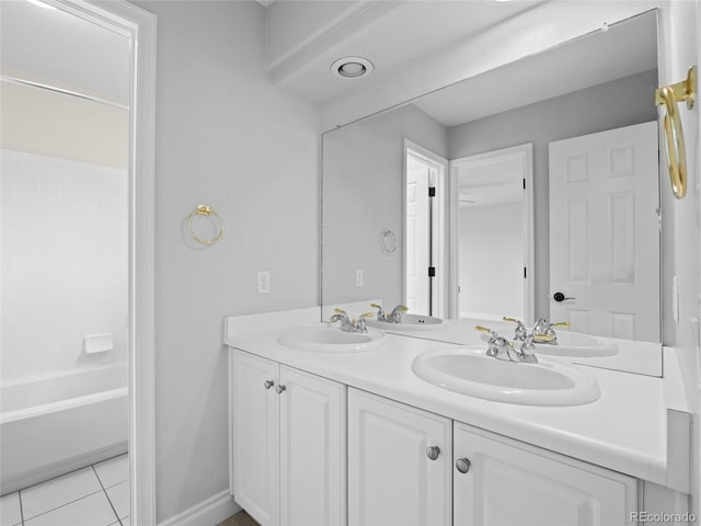 full bathroom featuring baseboards, double vanity, tile patterned floors, and a sink
