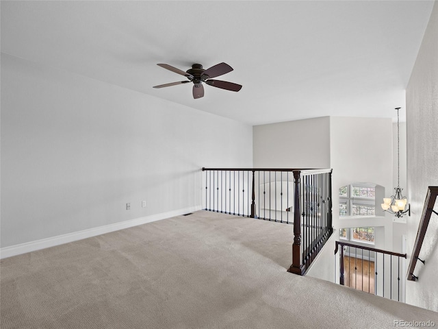carpeted empty room featuring baseboards and ceiling fan with notable chandelier