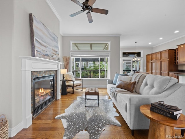 living room with crown molding, a ceiling fan, and a glass covered fireplace